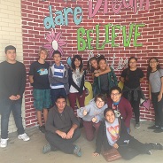Orchestra students stand in front of a mural